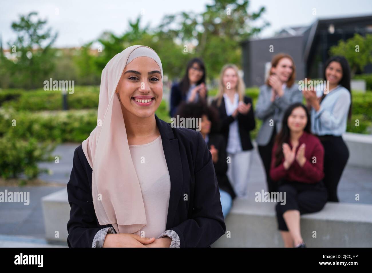 Young woman with hijab smiles applauded by her co-workers Stock Photo ...
