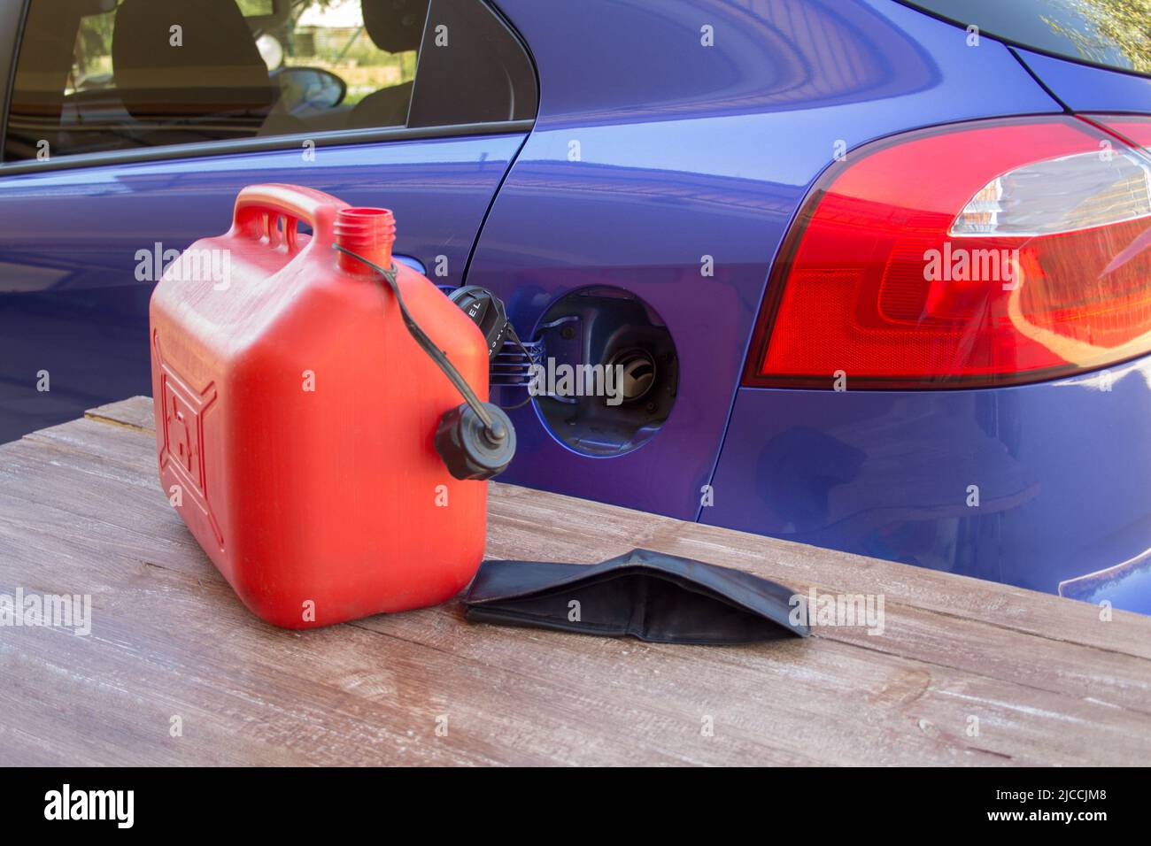 Image of a red jerrycan and an empty wallet next to the tank of a car without gasoline. Reference to the current expensive fuel and constant increase Stock Photo