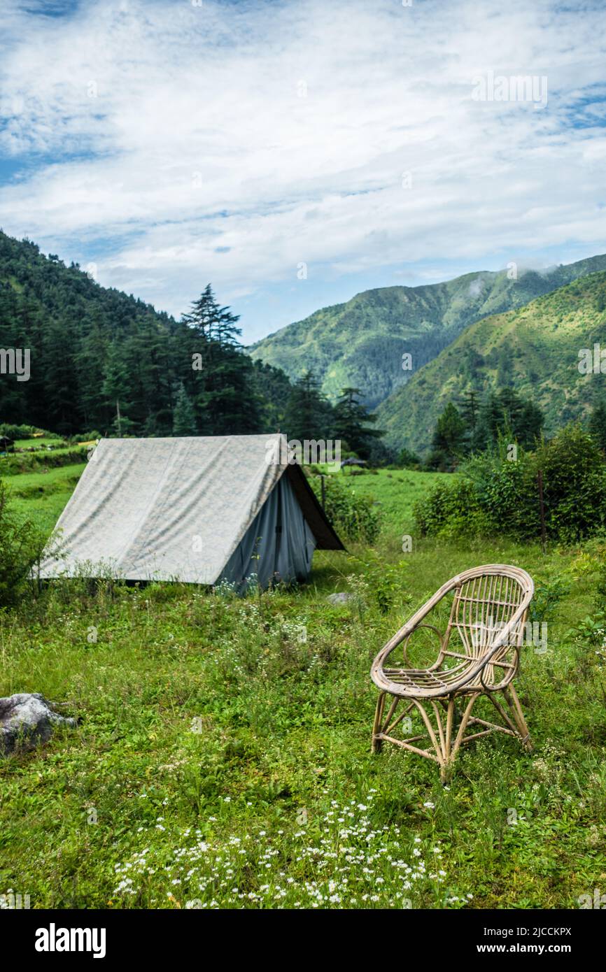 A tourist place in the meadows with a camp and a bamboo chair with mountains in the background. Uttarakhand India. Stock Photo