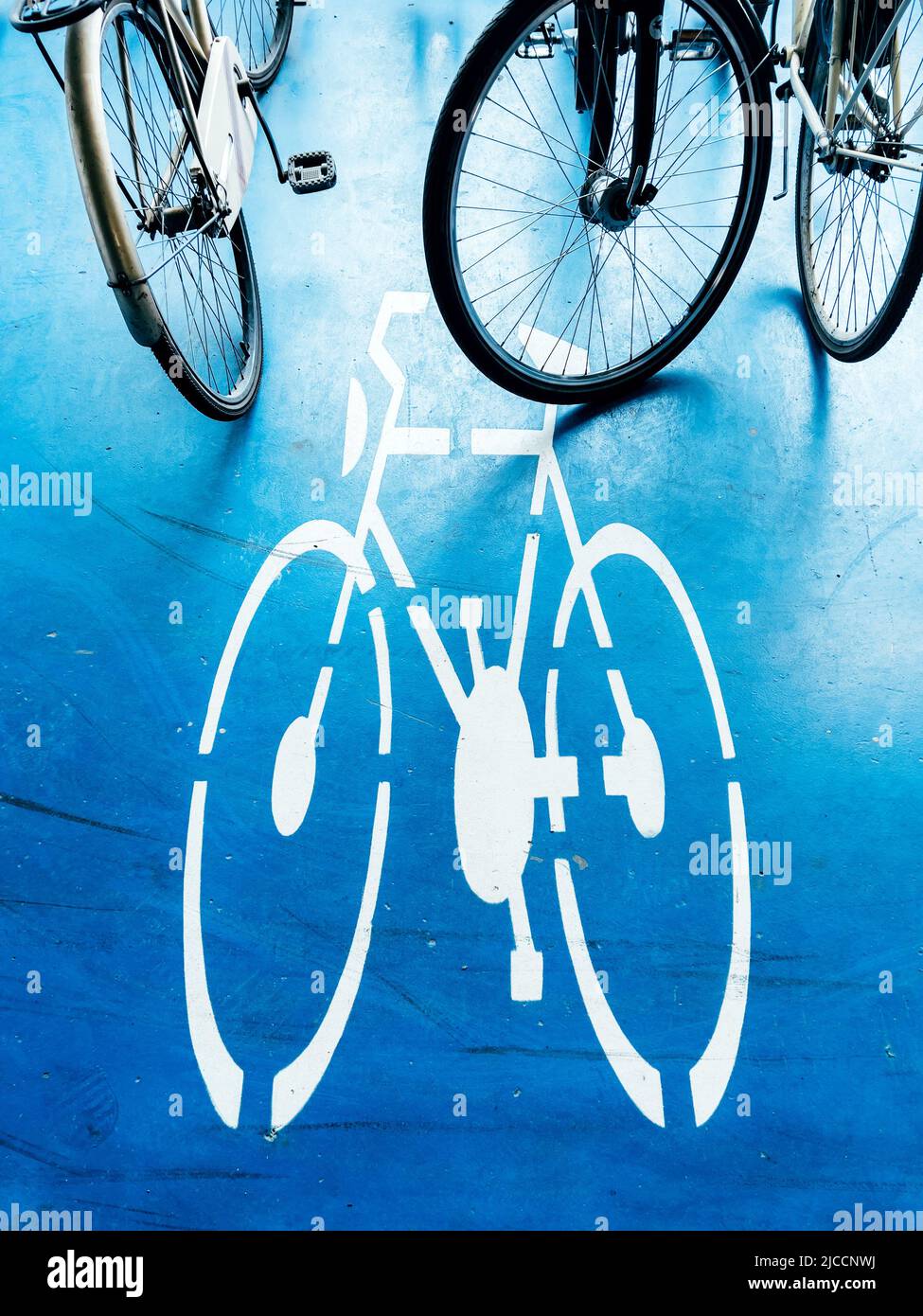 Bicycle parking area with bike pictogram symbol on ground and wheels in the background Stock Photo
