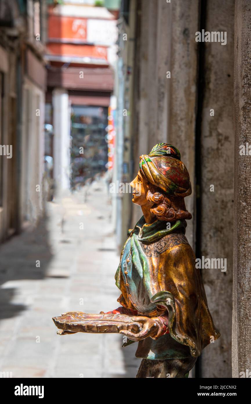 Side view of a wooden statue smiling and keeping a dish in the hands Stock Photo