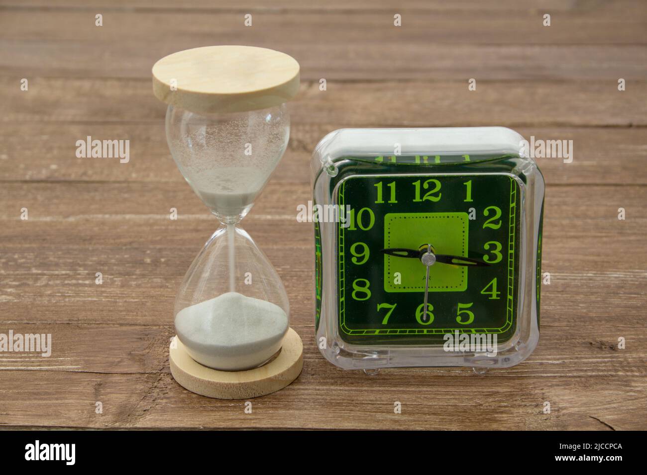 Image of an hourglass and a table clock. Reference to the passage of time Stock Photo