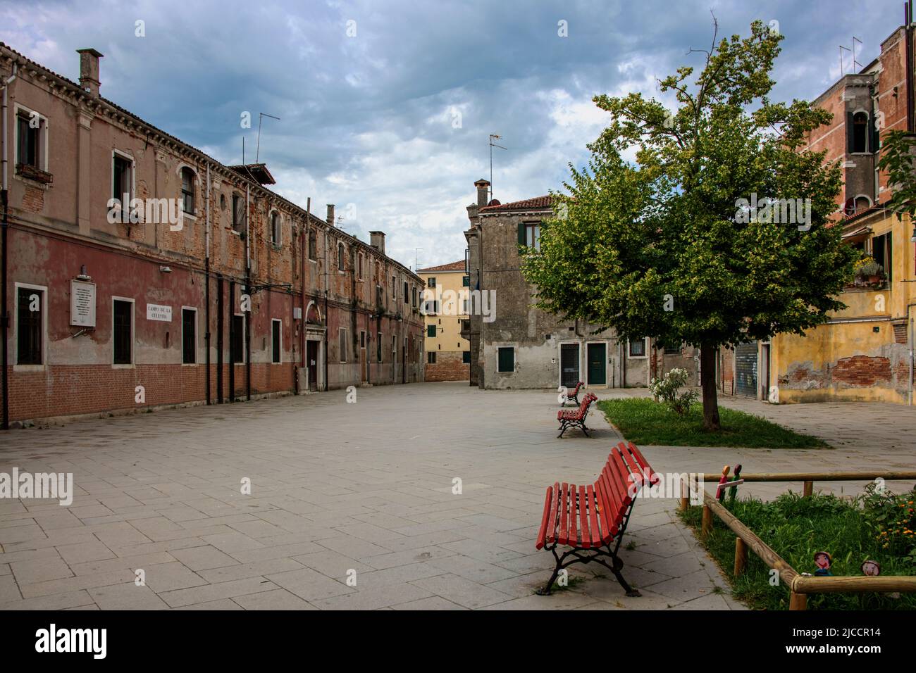 Empty public place with benches and trees under the cloudy sky Stock Photo