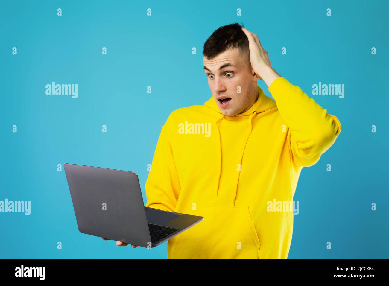 Confused Guy Using Laptop Scratching Head Having Problem, Blue Background Stock Photo
