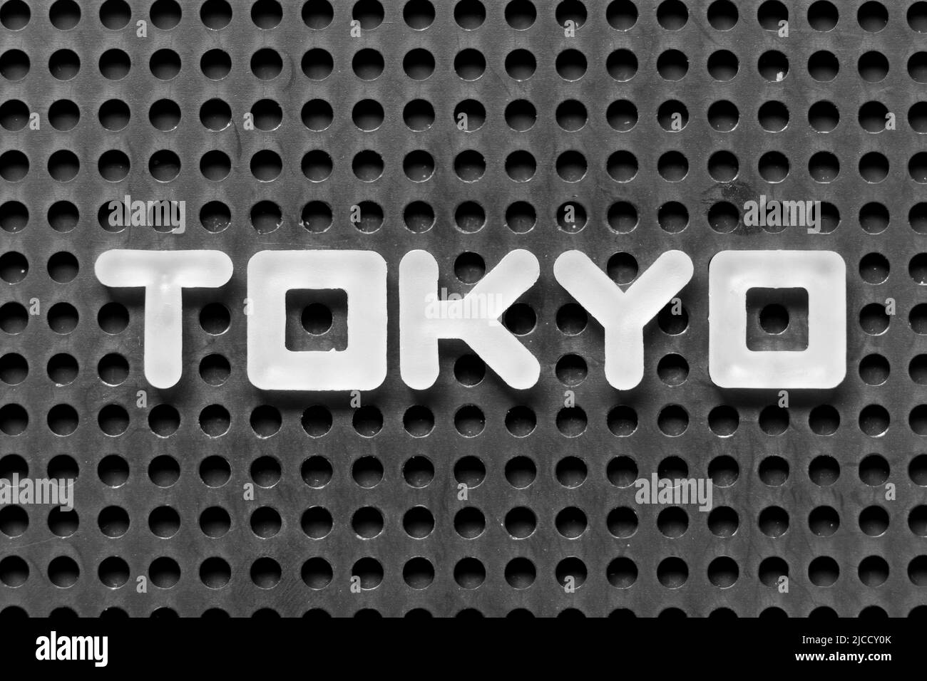 White alphabet letter in word tokyo on black pegboard background Stock Photo