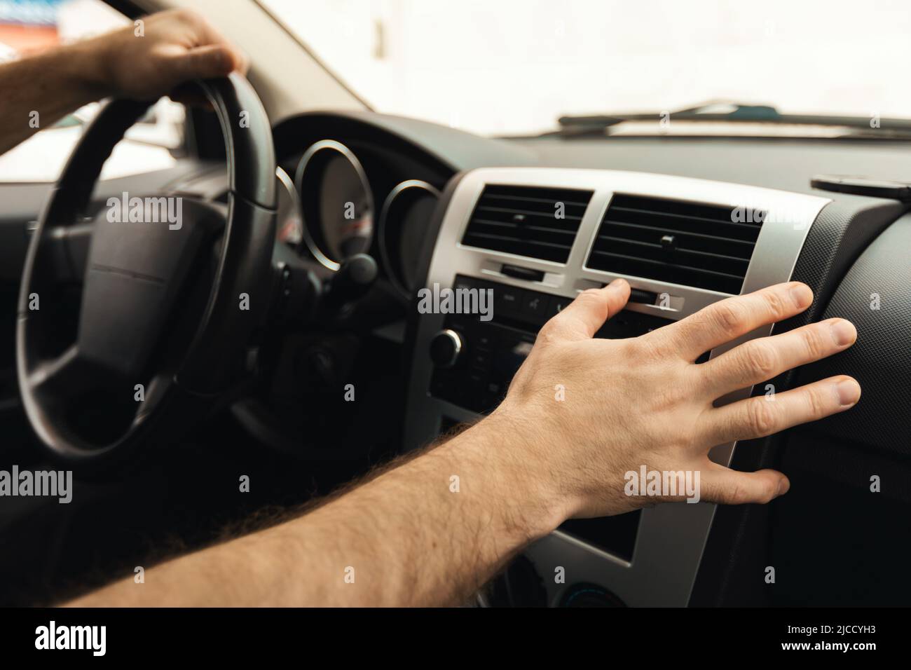 Male Driver Pushing Button On Control Panel Driving Car, Closeup Stock Photo