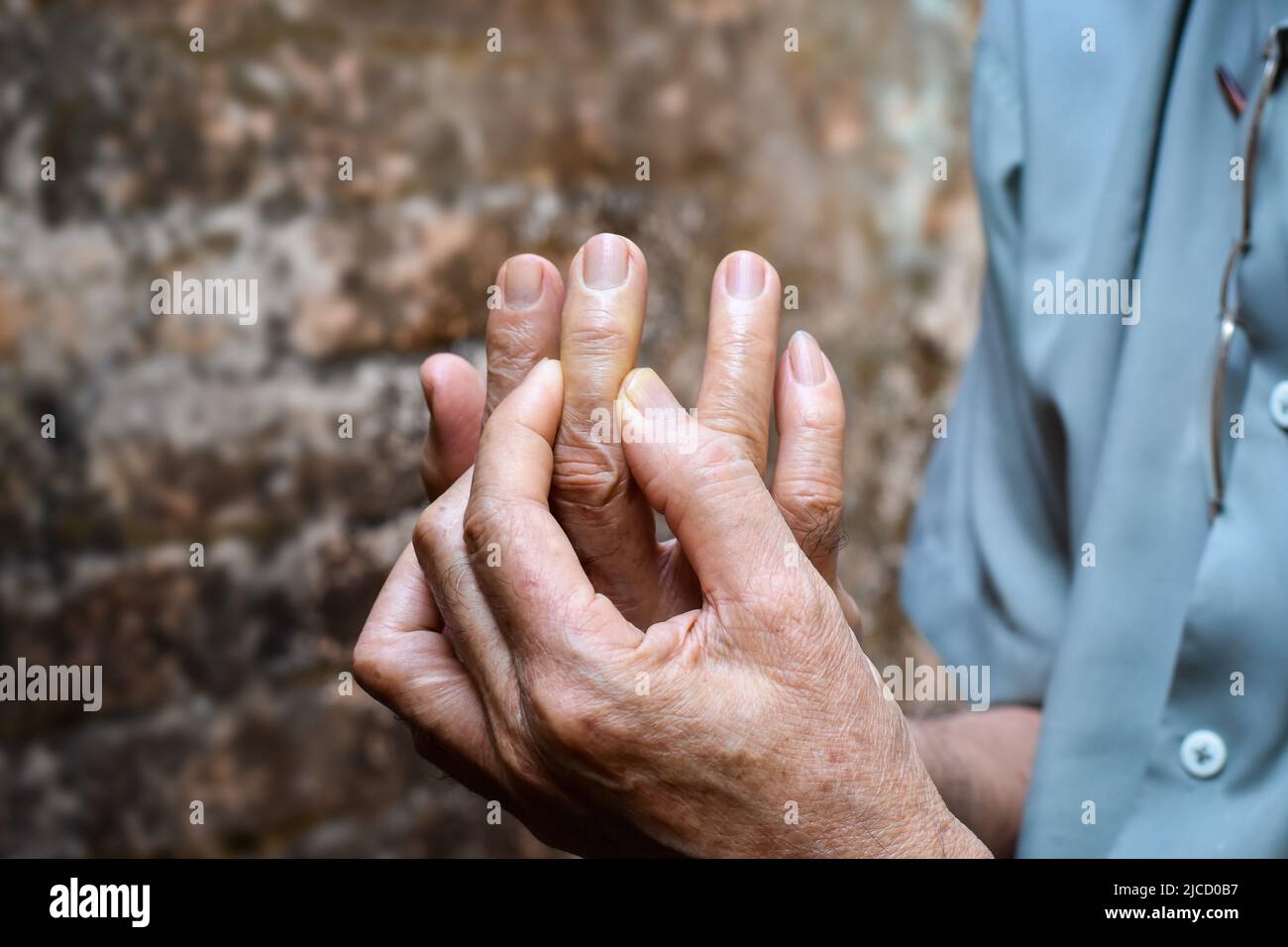 Middle finger pain in Asian old man. Concept of cellulitis and finger problems. Stock Photo