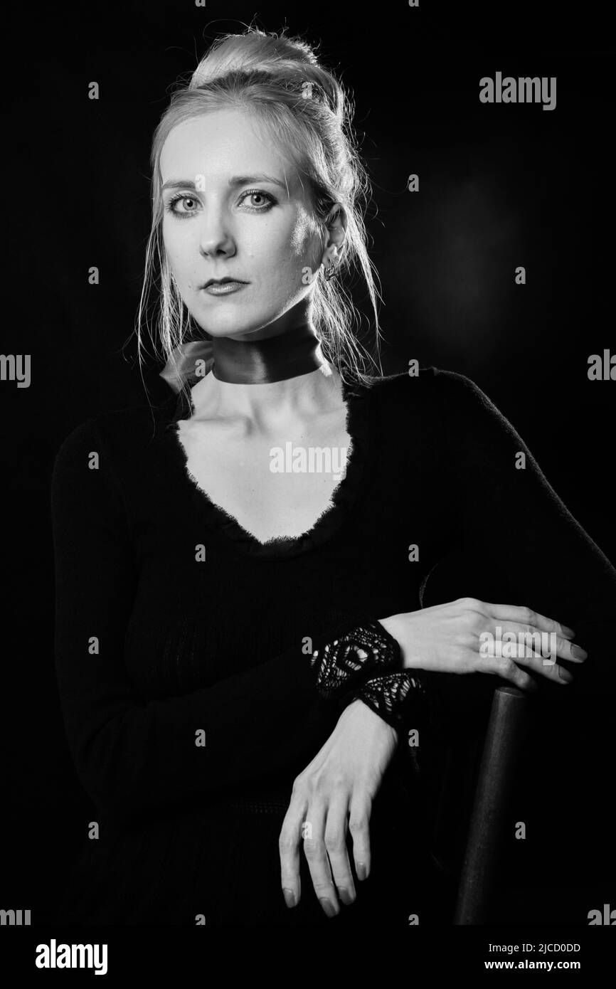 Senior woman in black dress looking at camera serious. Dark background studio shot. monochrome Stock Photo
