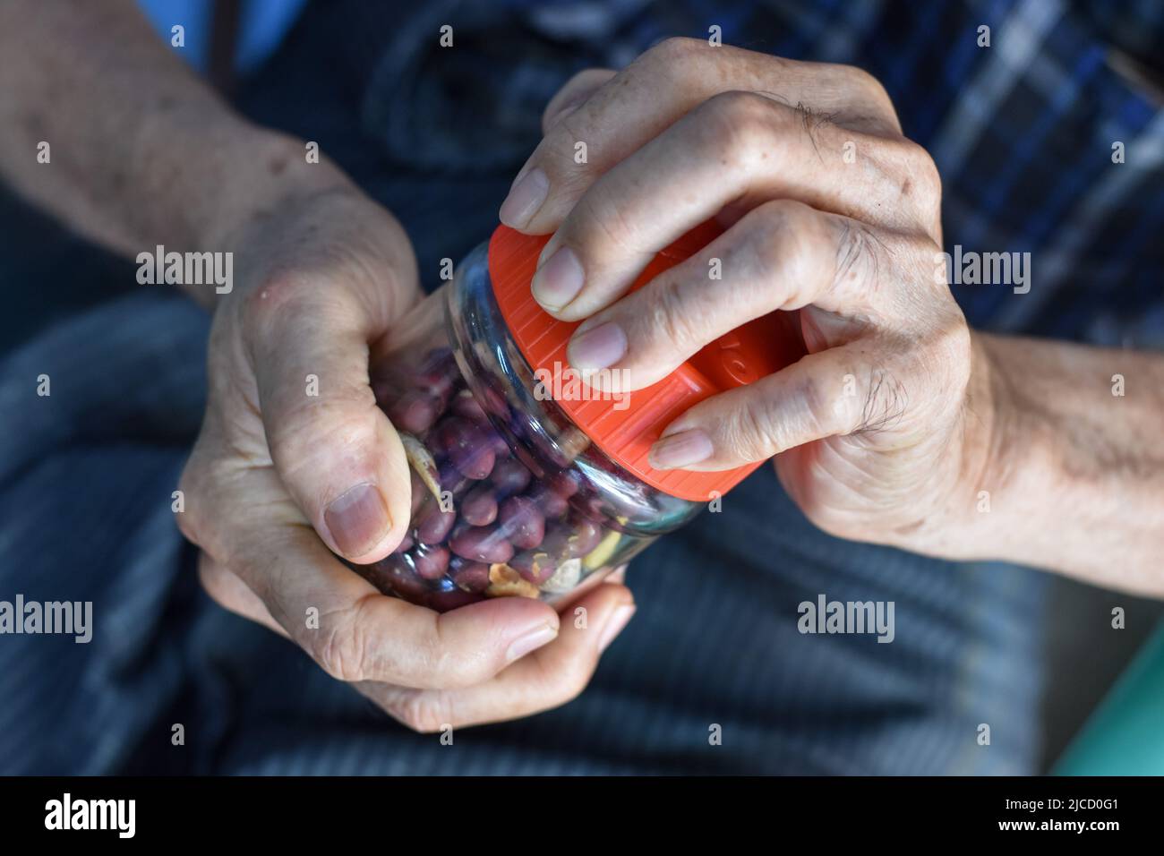 Asian Chinese man screwing the cap of glass bottle. Concept of hand muscle strength and power. Stock Photo