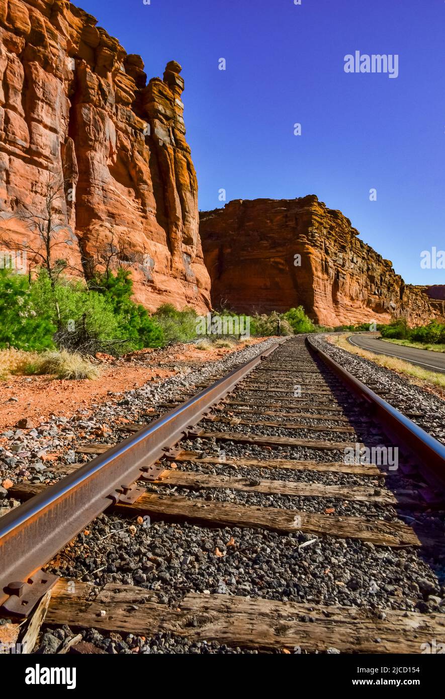 Railroad At The Bottom Of A Canyon Next To Layered Geological 