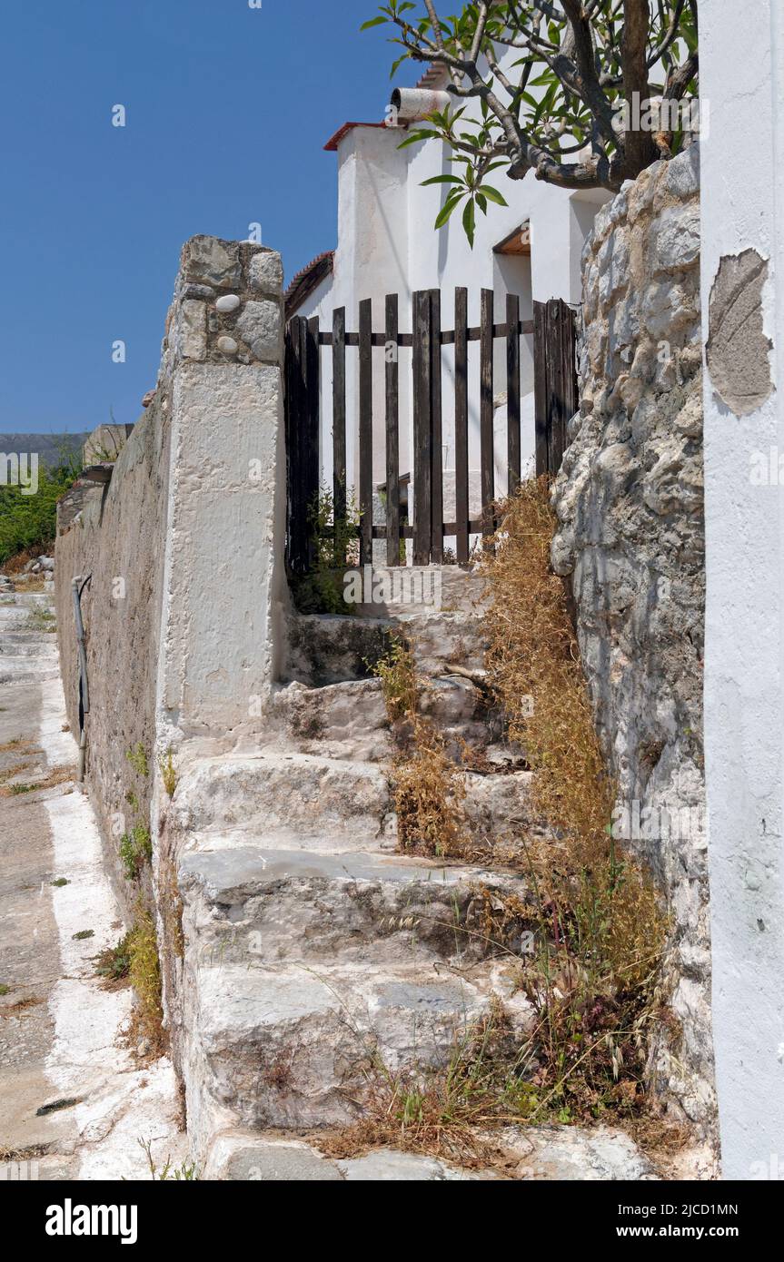 Gate and whitewashed stone walls with uneven steps. Megalo Chorio mountain village, Tilos, Dodecanese, Rhodes, Greece Stock Photo