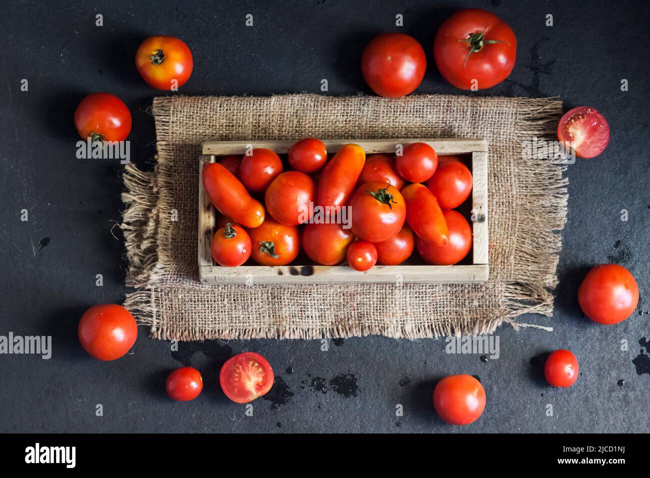 Fresh red tomatoes in wooden box on black background. Flat lay, top ...