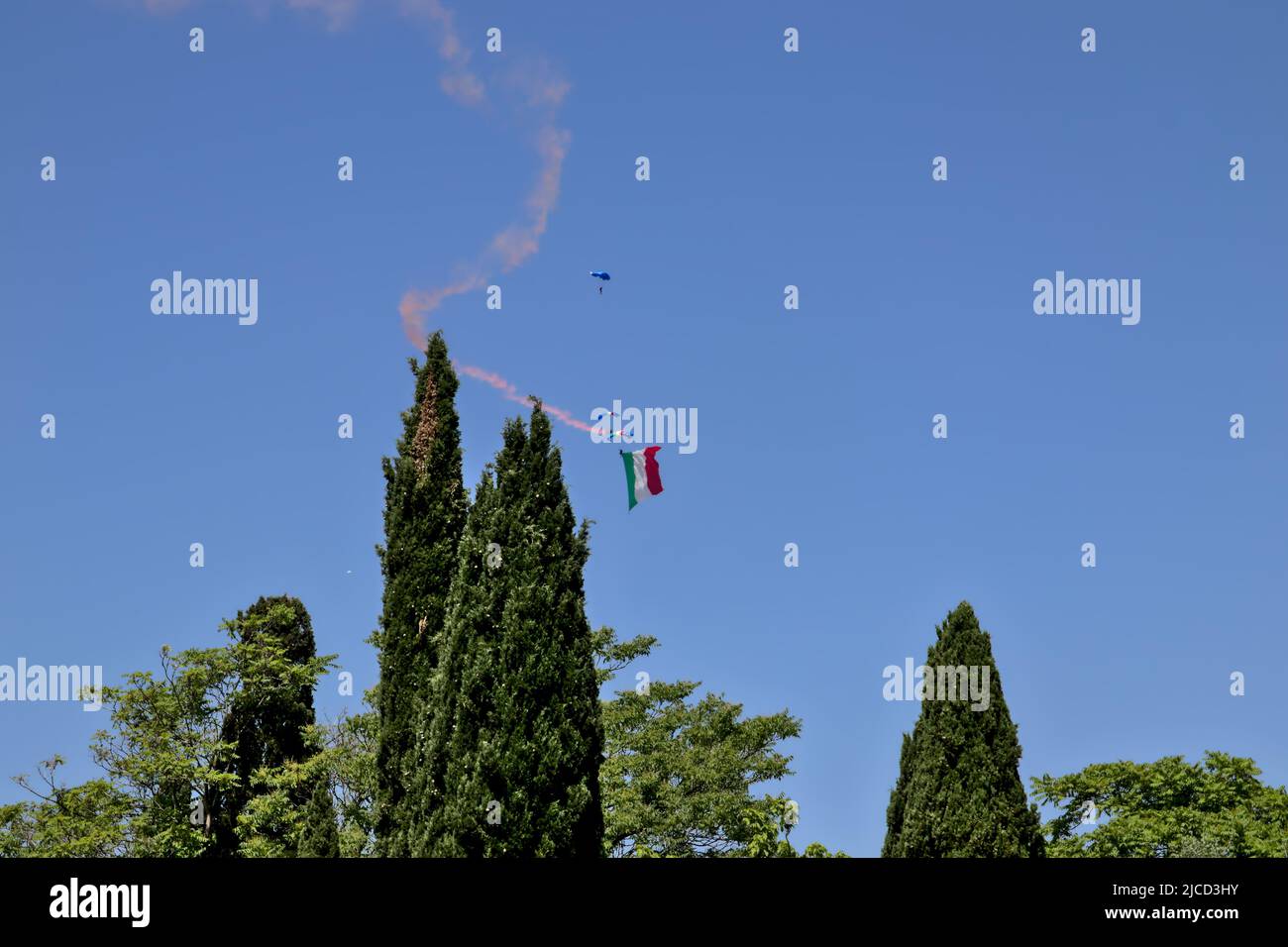 A military paratrooper launched from a helicopter unrolls the Italian flag. Stock Photo