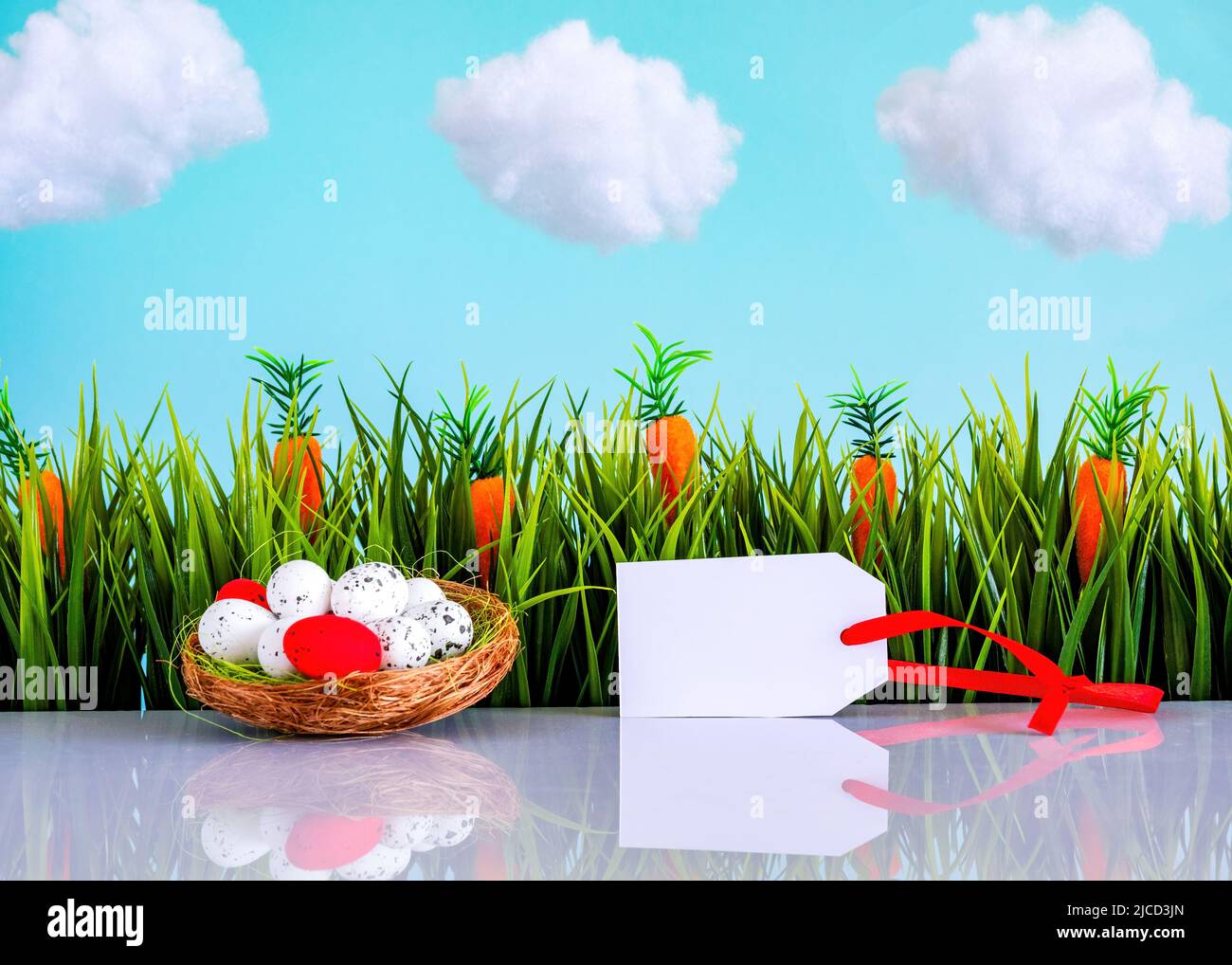 Easter background with colorful eggs, green grass, tag and blue sky with white clouds Stock Photo