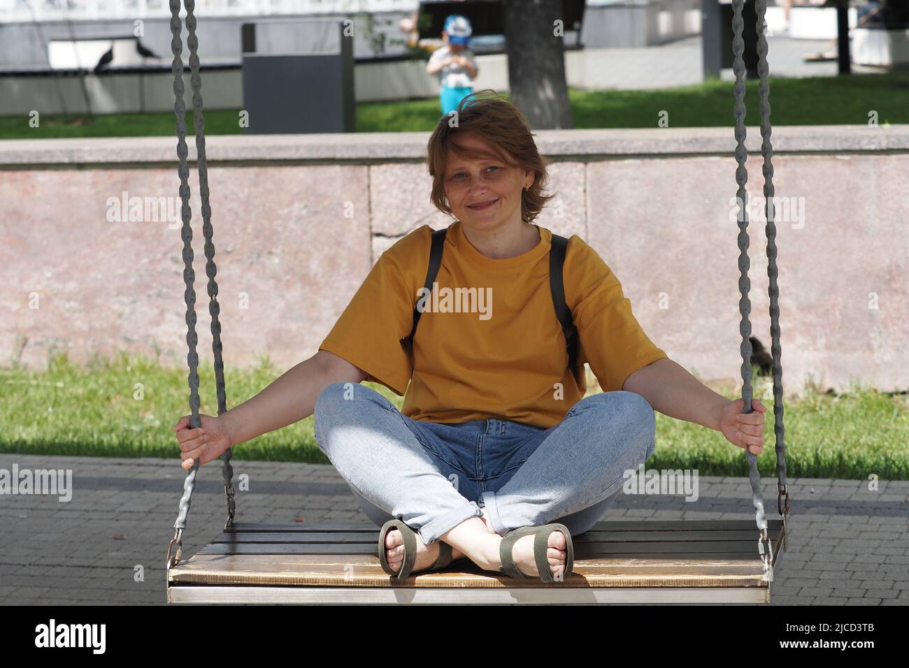Portrait of a woman. A girl of European appearance in a yellow T-shirt is resting in the park in Stock Photo