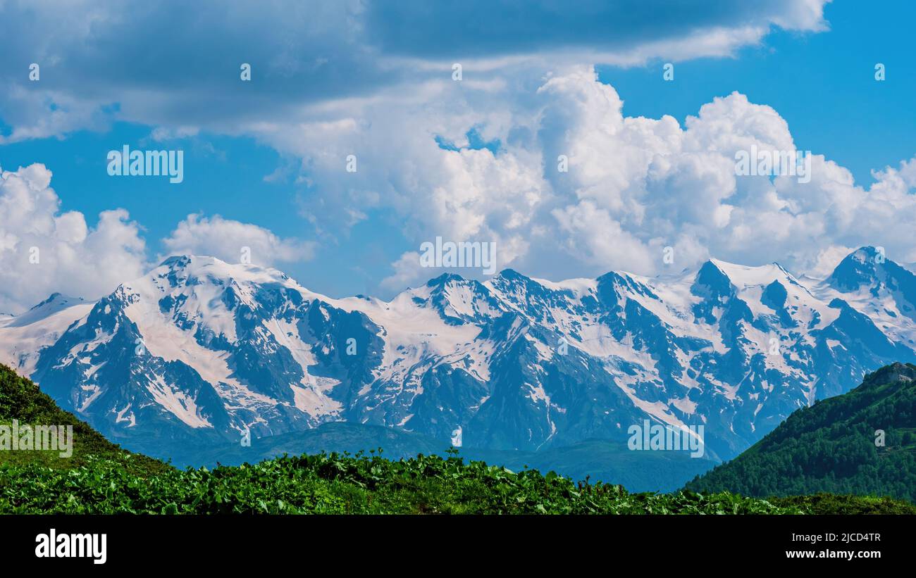 Idyllic landscape with blue sky, green grassland and snowcapped mountain top. Svanetia region, Georgia Stock Photo