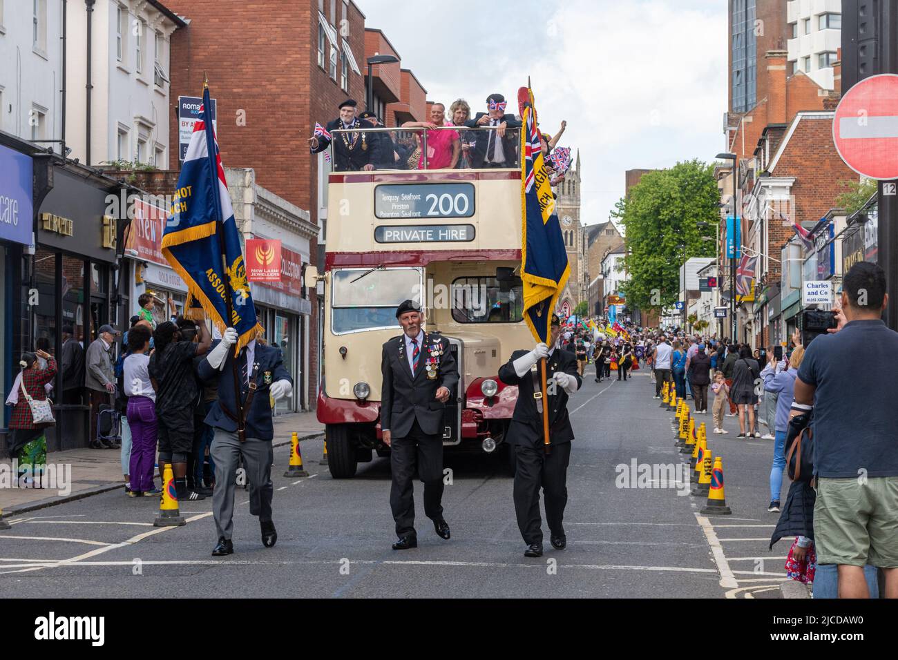 Royal British Legion standard bearers and open-topped bus with Normandy veterans in the Grand Parade at Victoria Day event in Aldershot, Hampshire, UK Stock Photo