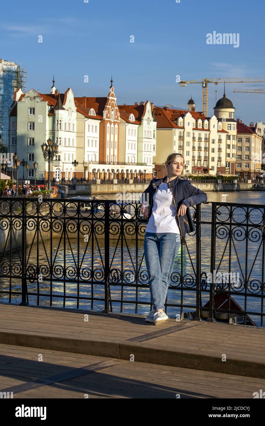 Blonde stands on bridge against backdrop of a beautiful city embankmen Stock Photo