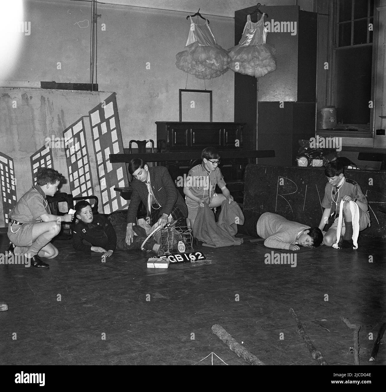 1960s, historical, several boy scouts in a school hall doing first aid exercises, as part of their training, to gain their safety badges, England, UK. First aid is an important skill for every scout, as with some knowledge of it, they are able to provide immediate care and assistance to some who is hurt or who becomes ill. Stock Photo