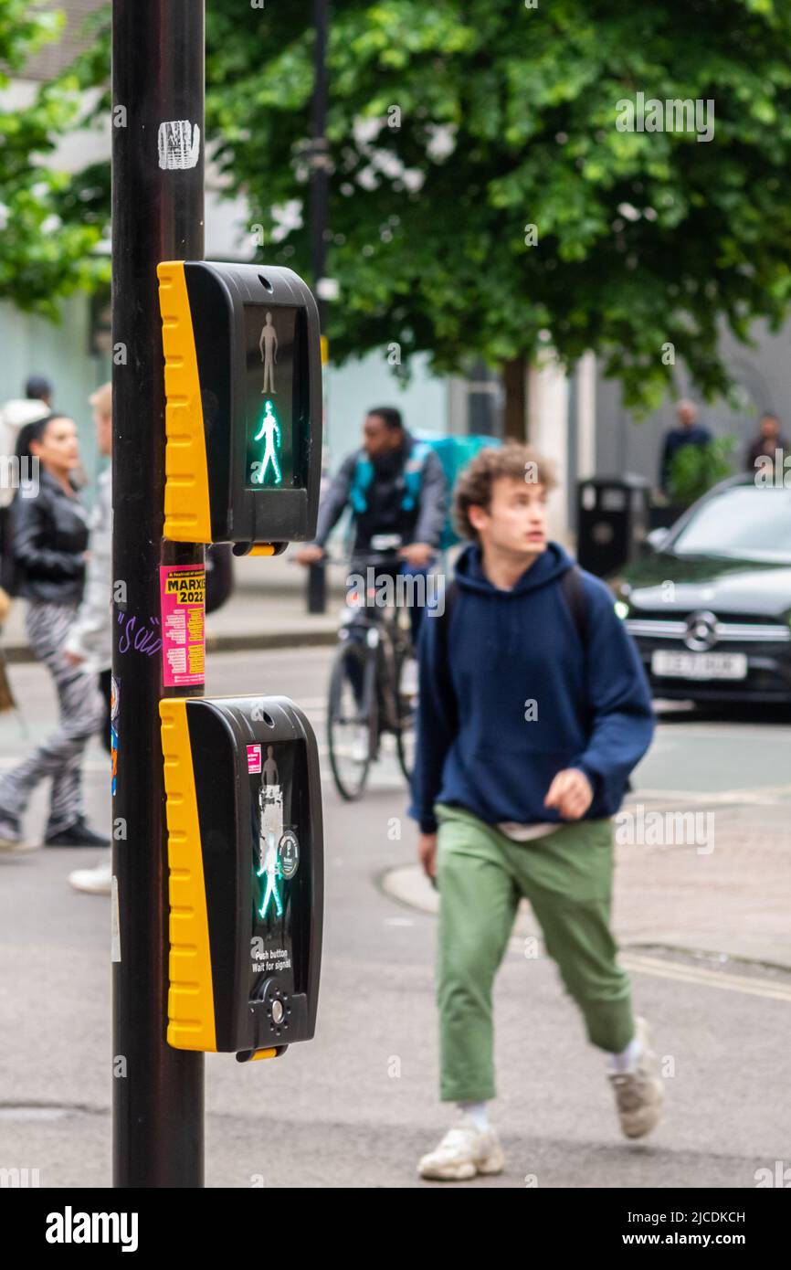 Pedestrian crossing the road at Market Street, Manchester. A puffin crossing displays the 'green man' as someone crosses the road. England, UK Stock Photo