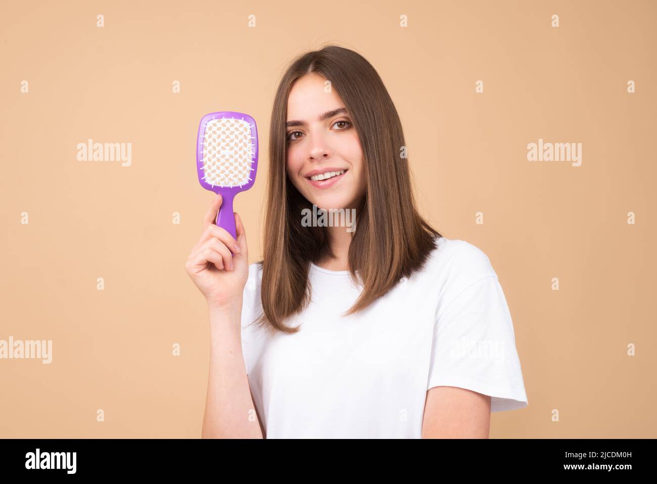 Brushing Hair. Portrait young woman brushing straight natural hair with comb. Girl combing hair