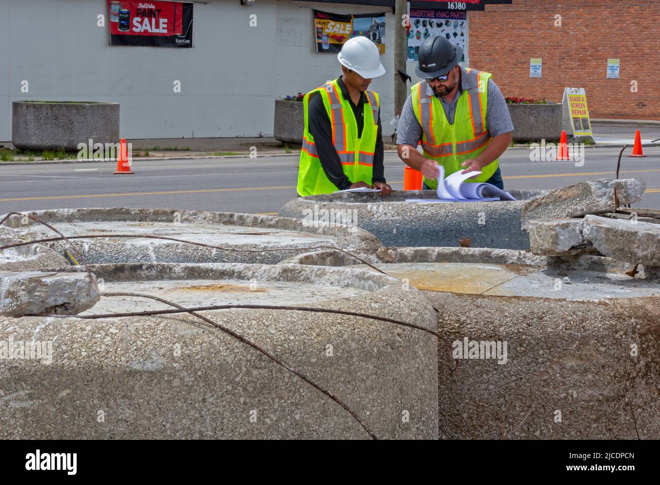 Detroit, Michigan - Construction workers look over plans for streetscape improvements on East Warren Avenue where there are many empty storefronts. Th Stock Photo