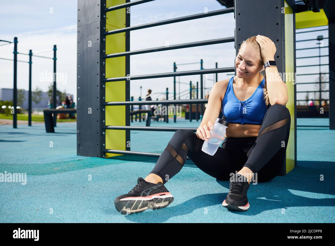 Cheerful attractive girl in sportswear sitting on ground at outdoor