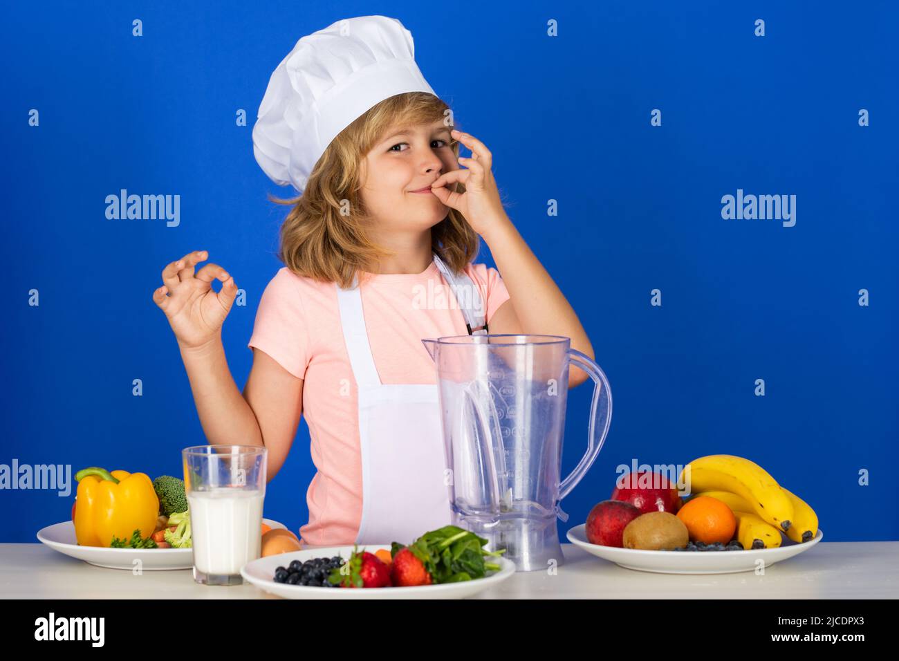 Portrait of a 7, 8 years old child in cook cap and apron making fruit