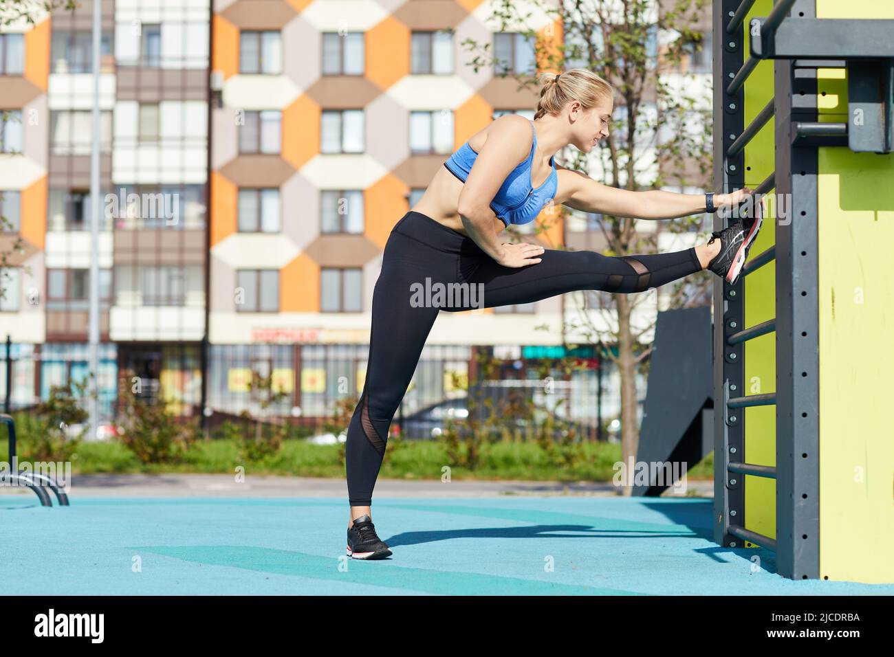 Positive flexible young woman in sports bra and leggings using exercise