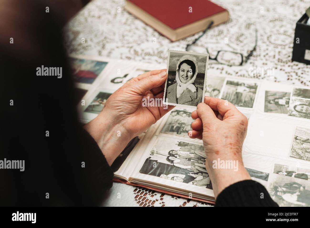 Elderly woman hands holding black and white photo of the young woman. Passing of time concept Stock Photo