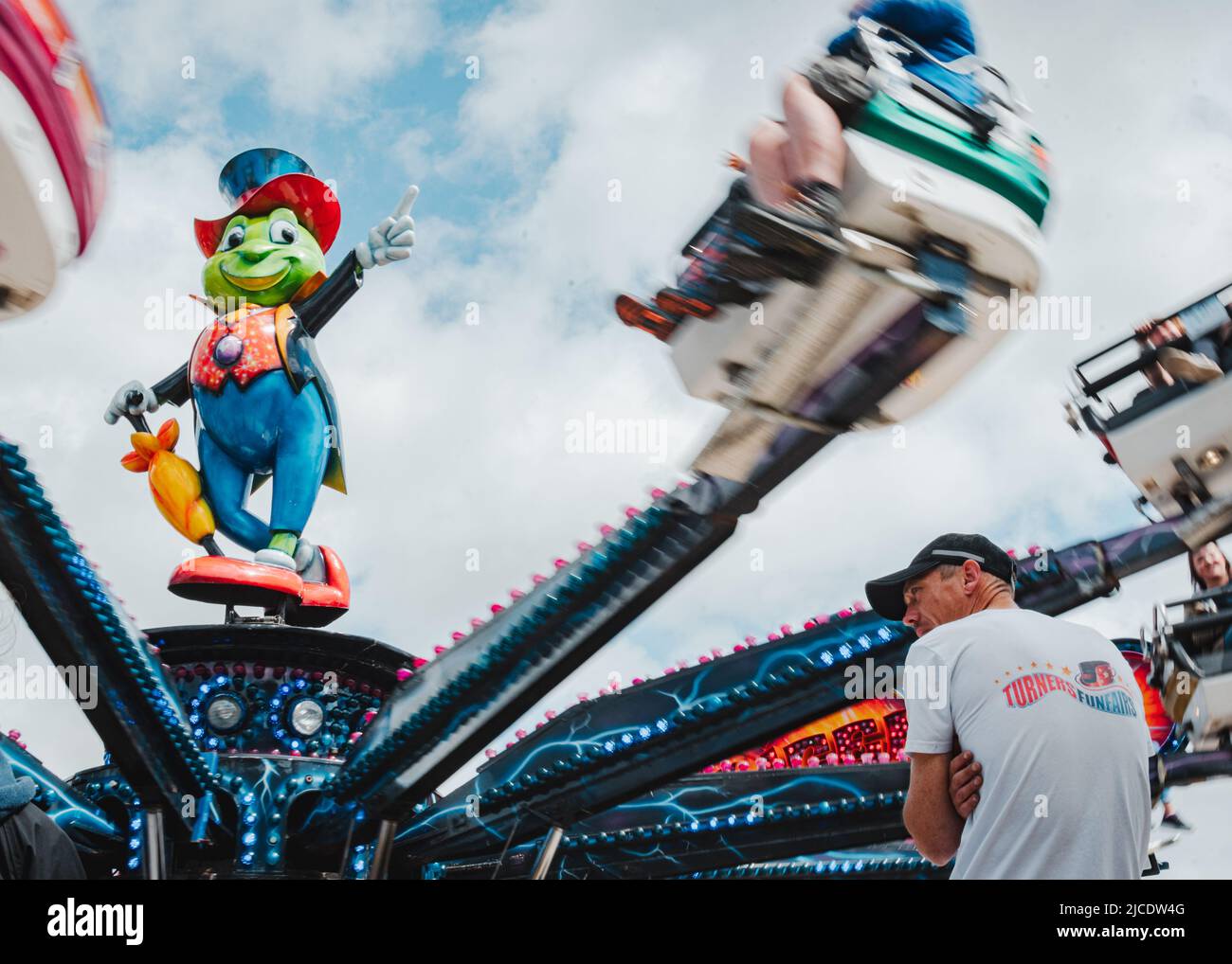 Man sitting in front of the Jiminy Cricket fair ride at Morpeth Fair ...
