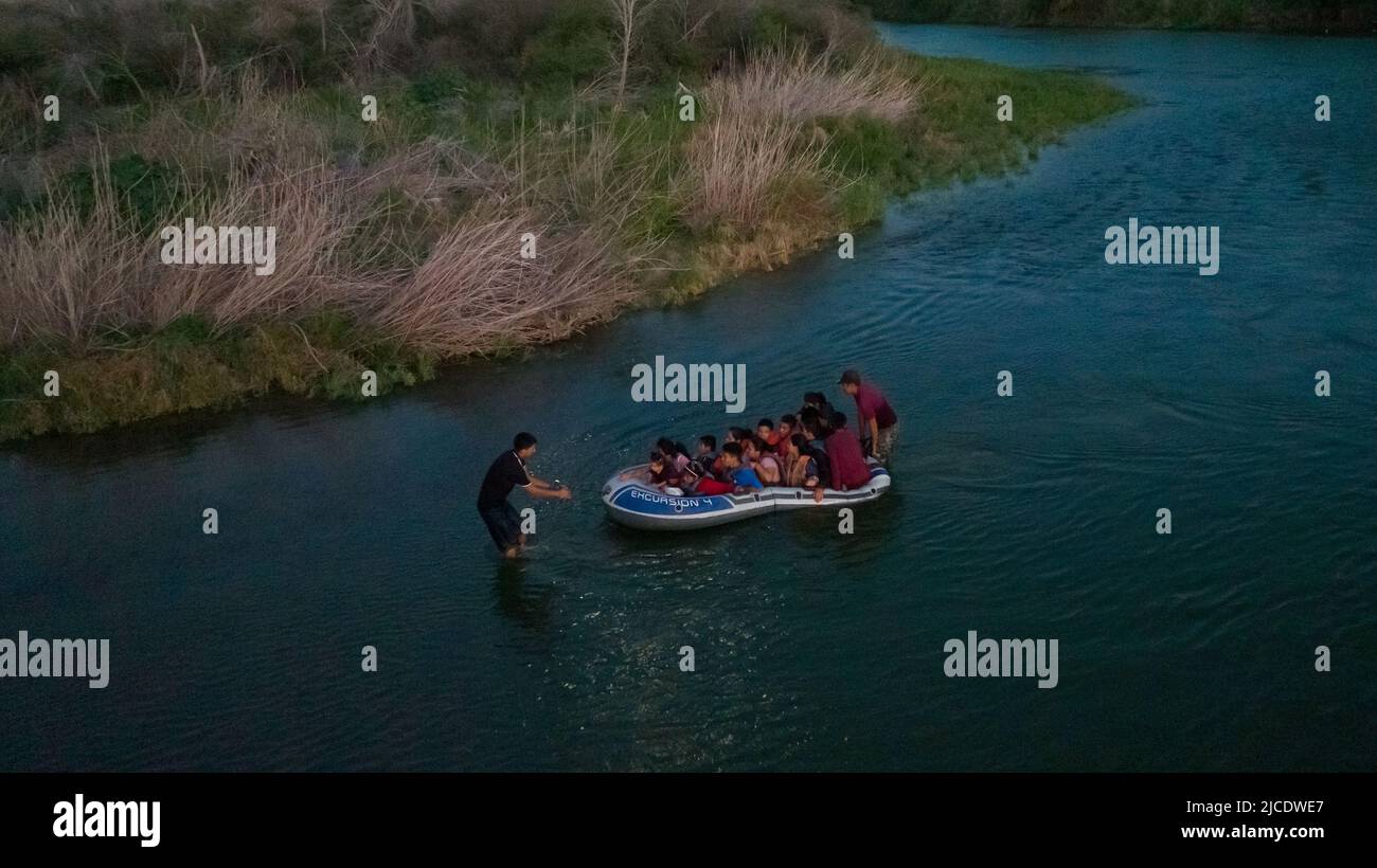 A smuggler pulls a raft full of asylum seeking migrants from Central and South America across the Rio Grande river into the United States from Mexico in Roma, Texas, U.S., June 11, 2022. Picture taken June 11, 2022. Picture taken with a drone. REUTERS/Adrees Latif Stock Photo