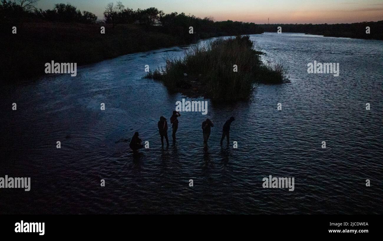 Asylum seeking migrants from Central and South America stand in a shallow part of the Rio Grande river while awaiting to be smuggled into the United States from Mexico in Roma, Texas, U.S., June 11, 2022. Picture taken June 11, 2022. Picture taken with a drone. REUTERS/Adrees Latif Stock Photo