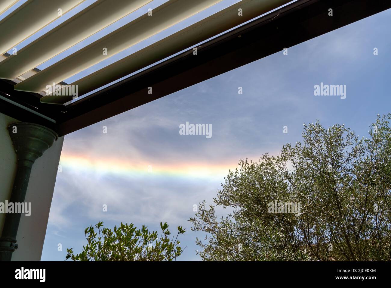 Colorful iridescent cloud, Beautiful Rainbow cloud over oliver trees and pergola La Rochelle France Stock Photo