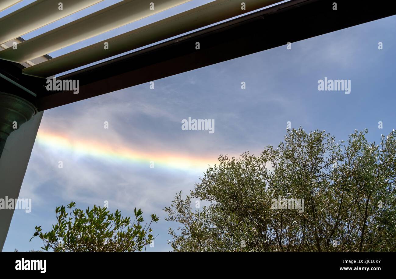 Colorful iridescent cloud, Beautiful Rainbow cloud over oliver trees and pergola La Rochelle France Stock Photo