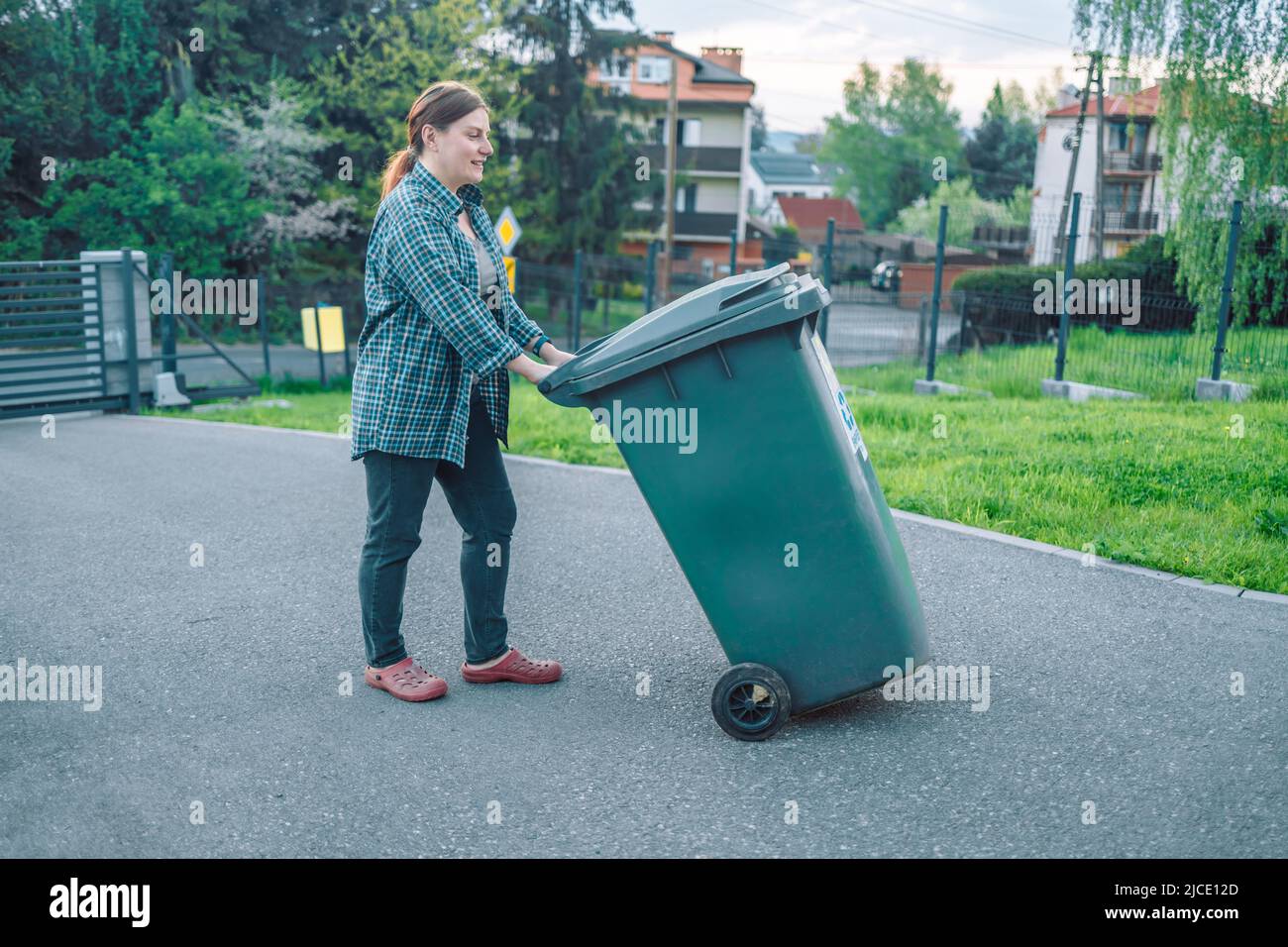 European 20s girl take out the trash can sorting garbage near a home