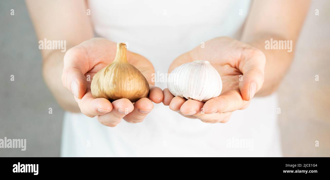 Person in white t-shirt on a grey background holds garlic and black ...