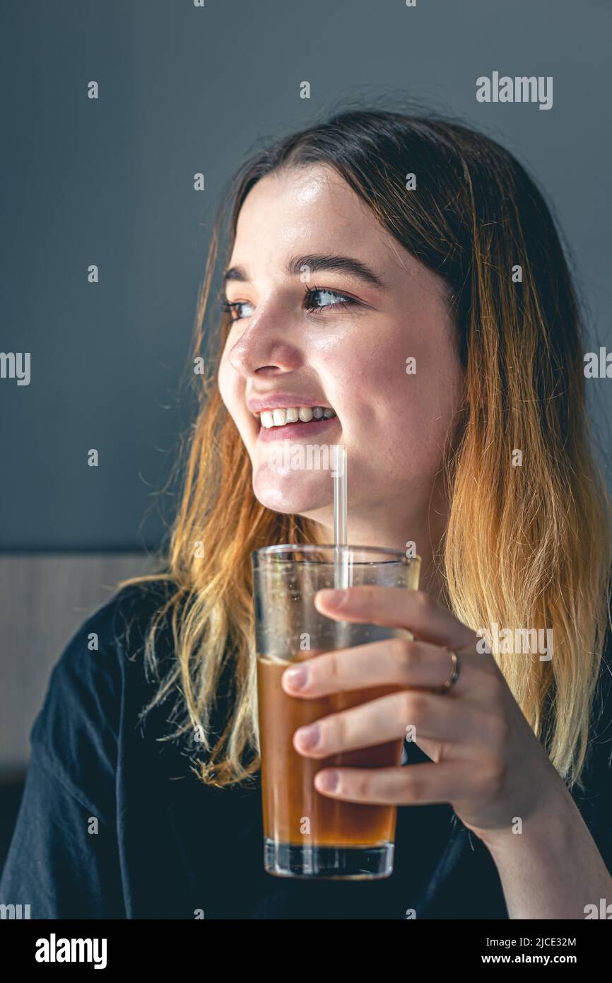 A young woman drinking cold summer coffee drink with ice and orange