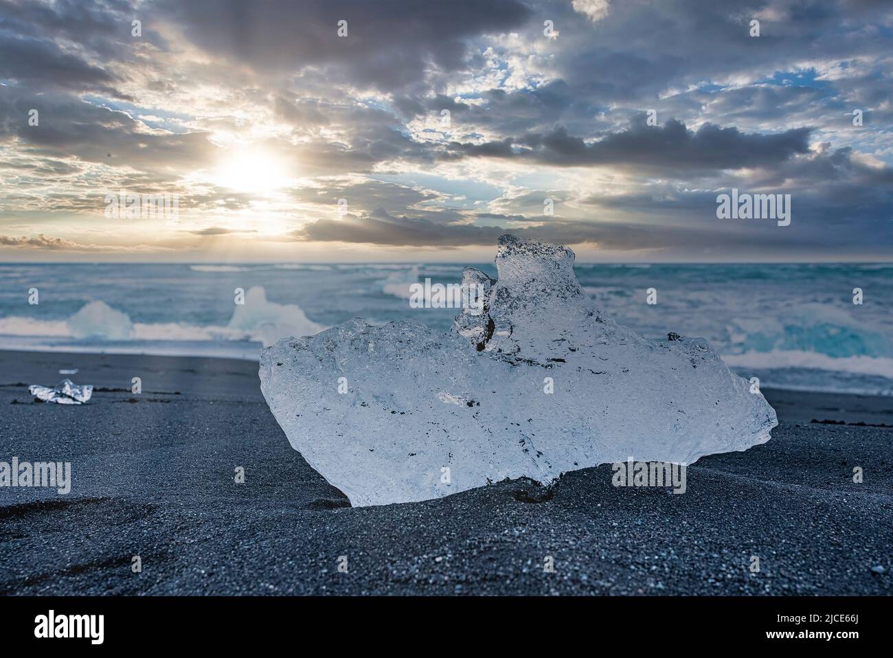 Close-up of iceberg on beautiful black sand beach against dramatic sky at sunset Stock Photo