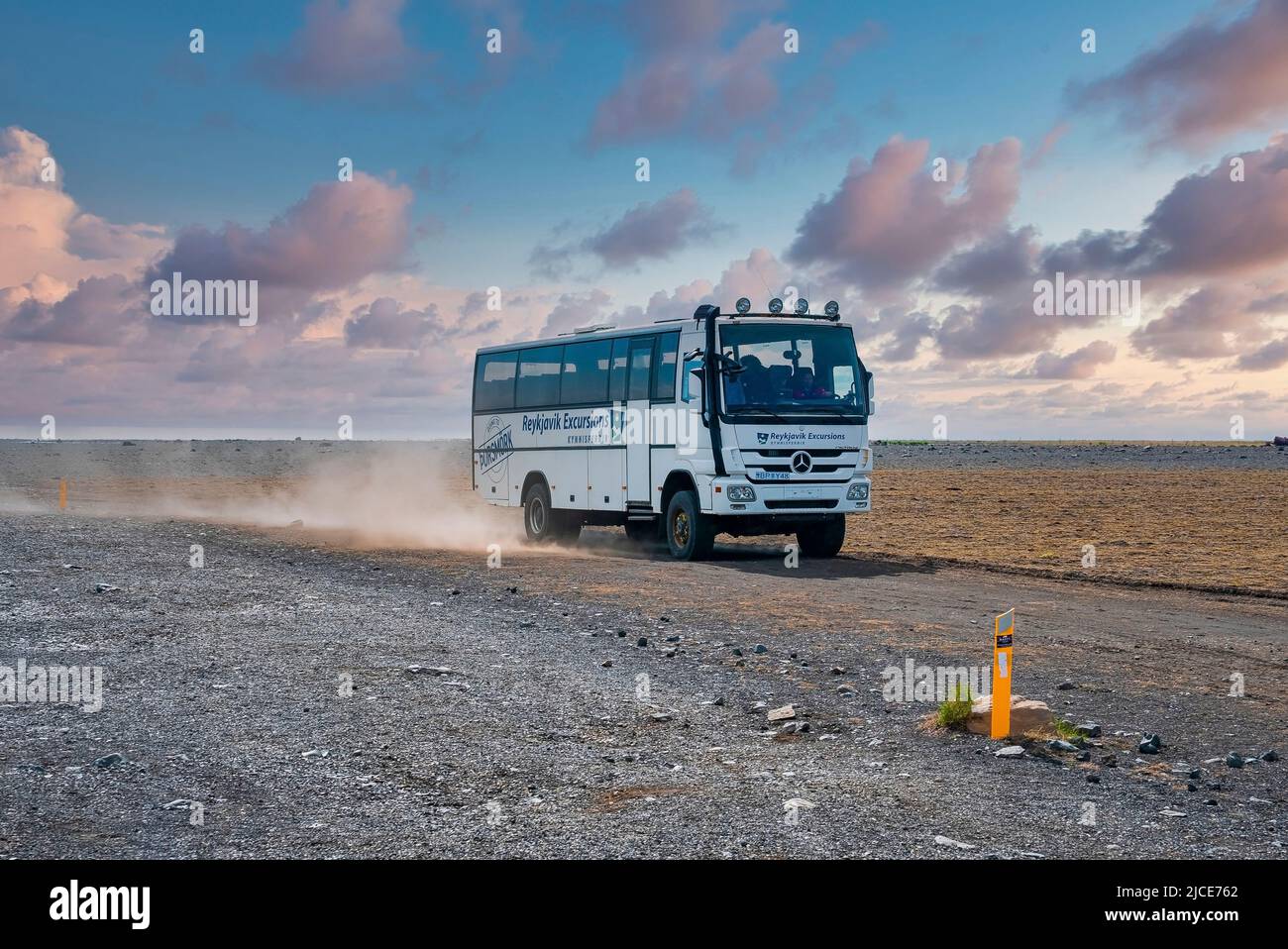 Reykjavik Excursions bus moving on lava sand at volcanic highland against sky Stock Photo