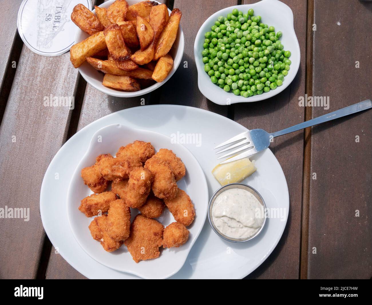 Excellent Scampi and chips with peas tartare sauce and lemon served outdoors at the Ellerby Hotel North Yorkshire Stock Photo