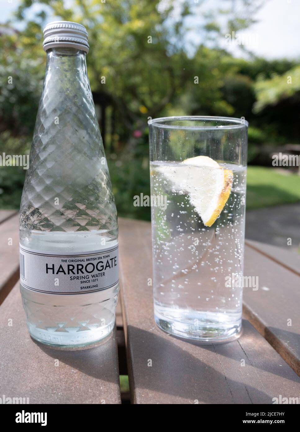 Harrogate Spa Sparkling mineral water, The Original British Spa Town Spring Water since 1571 bottle and glass with a slice of lemon  on an outside tab Stock Photo