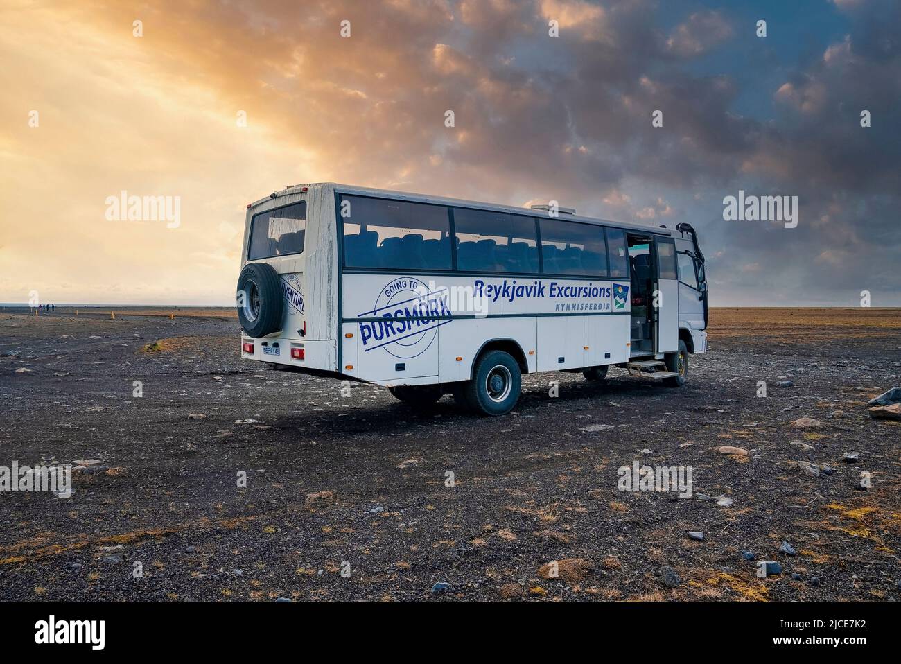 Reykjavik Excursions flybus parked on lava sand against cloudy sky during sunset Stock Photo