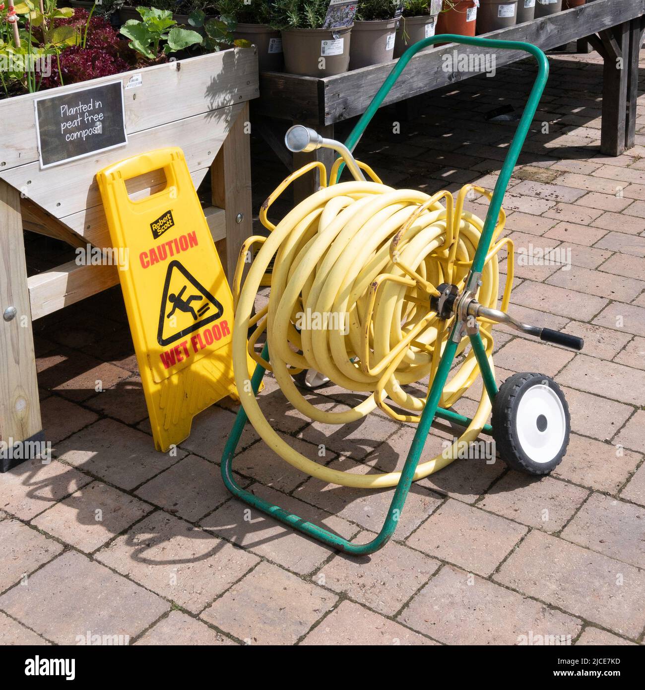 A market garden hose reel with yellow kink resisting hose on portable reels and having spray nozzles convenient deployment in a garden centre run out Stock Photo