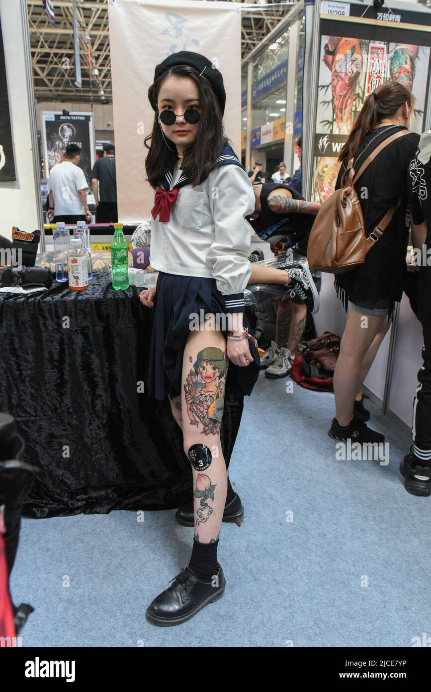 LANGFANG, CHINA - MAY 05 2019: A girl in a beret and round sunglasses shows  off a colored anime style tattoo on her leg. Demonstration of tattoos to  Stock Photo - Alamy