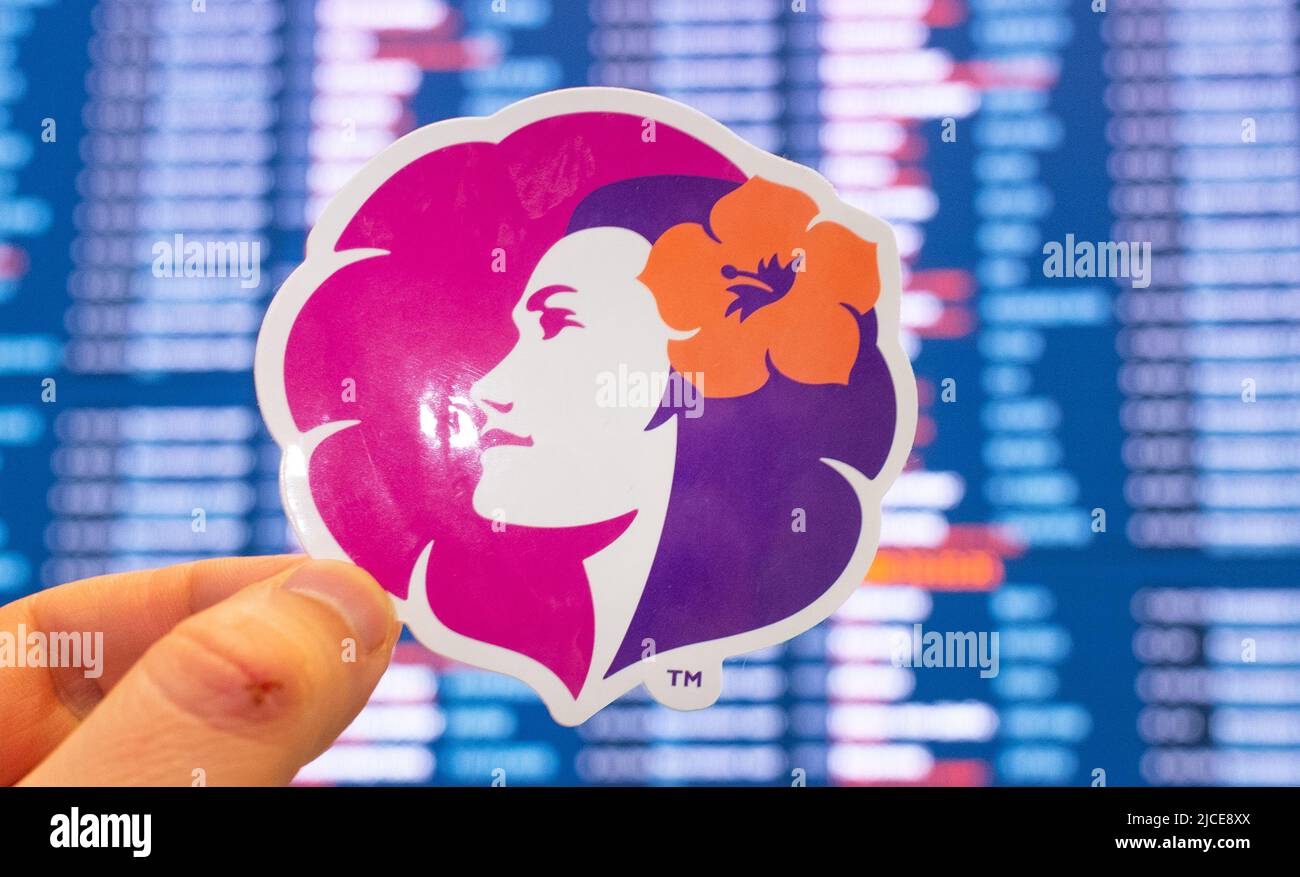 December 11, 2021, Honolulu, USA. The emblem of Hawaiian Airlines against the background of an electronic scoreboard with flight schedules at the inte Stock Photo