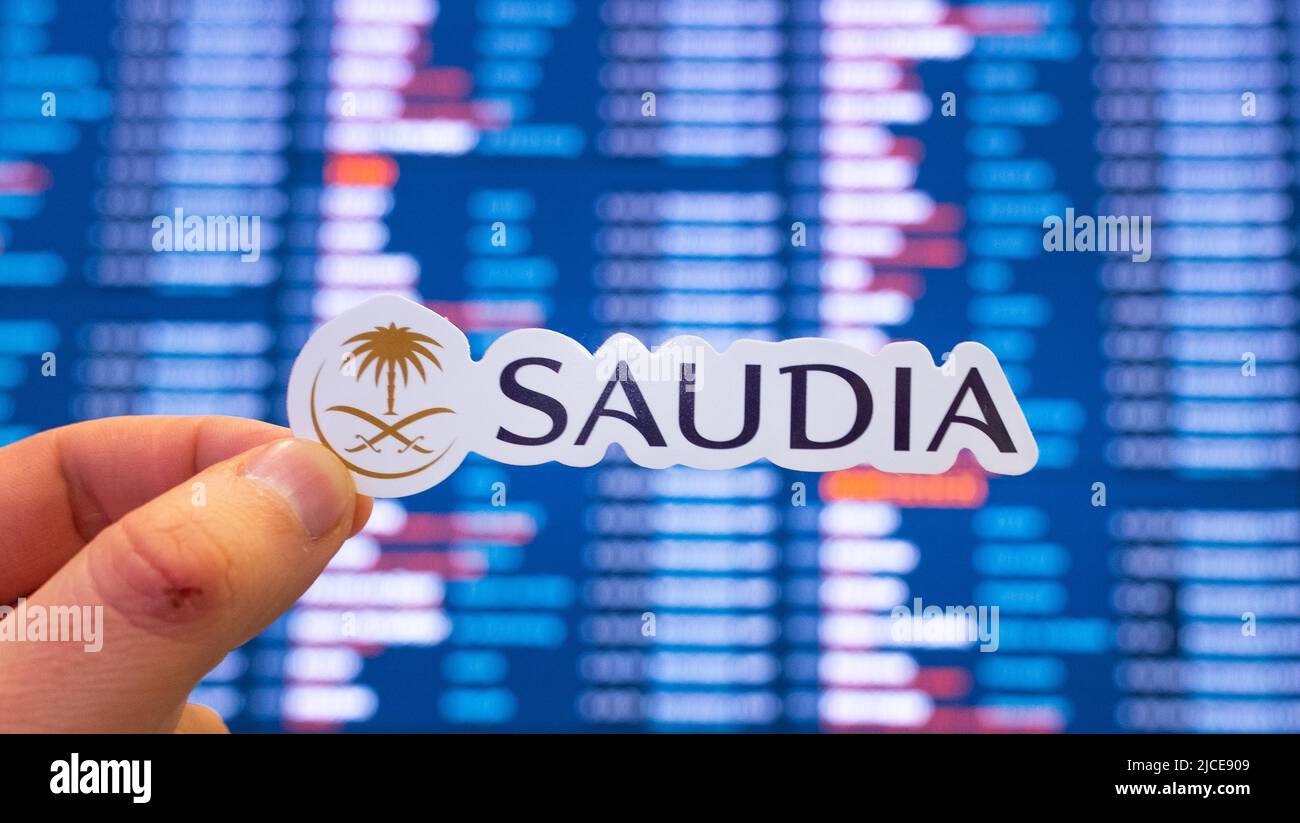 December 11, 2021, Jeddah, Saudi Arabia. The emblem of the Saudia airline against the background of an electronic board with a flight schedule at the Stock Photo