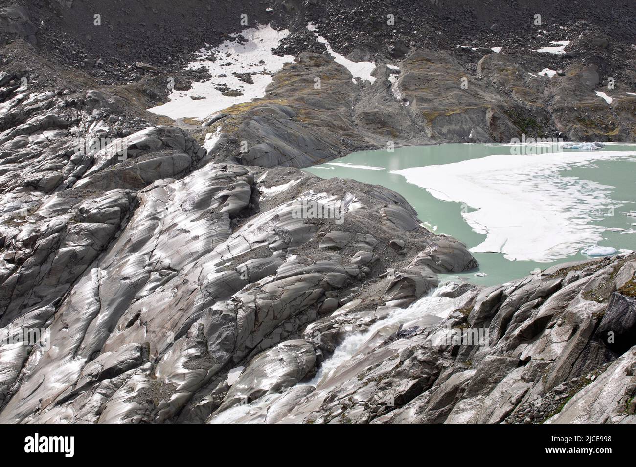 Source of rhone river, glacial lake fall as a waterfall between mountain rocks. High alps landscape of arid terrain. Stock Photo