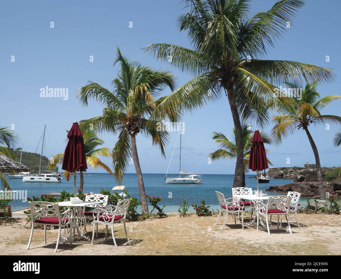 View of empty dining tables and chairs on a pretty sandy beach in Antigua Stock Photo