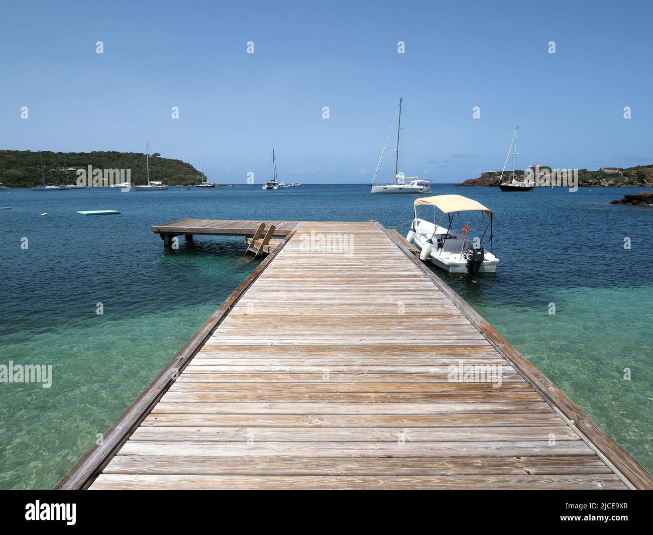 View looking along a wooden jetty stretching out into the Caribbean sea in Antigua Stock Photo